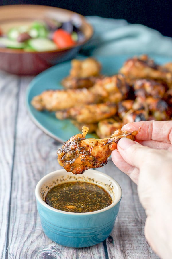A hand lifting one of the wings out of the marinade