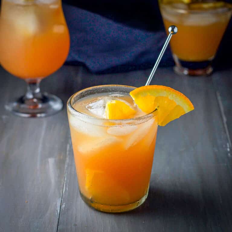 The double old fashioned glass filled with the rum drink with the two glasses behind it