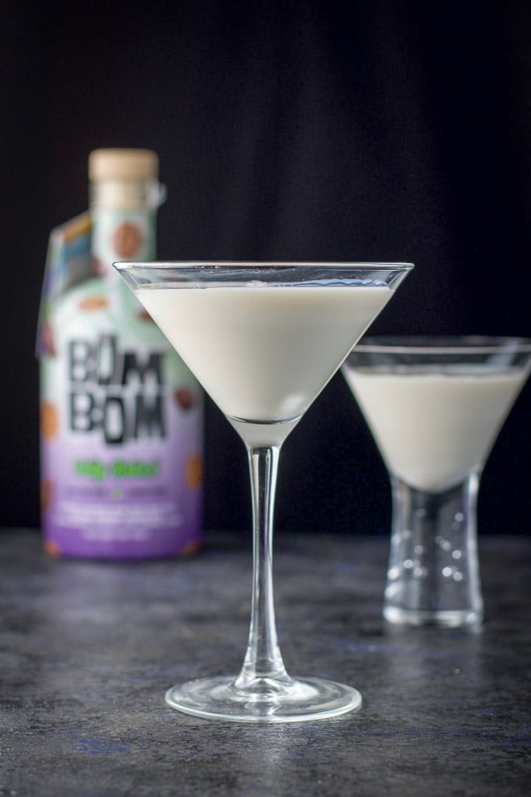 vertical view of the classic martini glass filled with the cream drink with another glass and bottle in the background