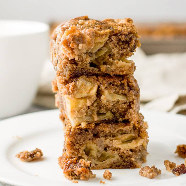 Three pieces of apple cake on a white plate with crumbs on it