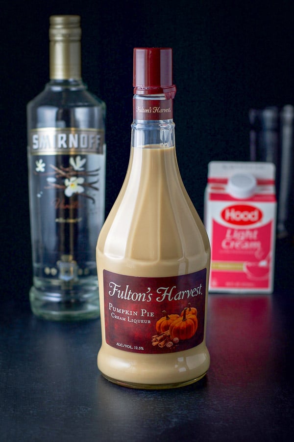 Pumpkin spice liqueur, vanilla vodka and light cream on a black table