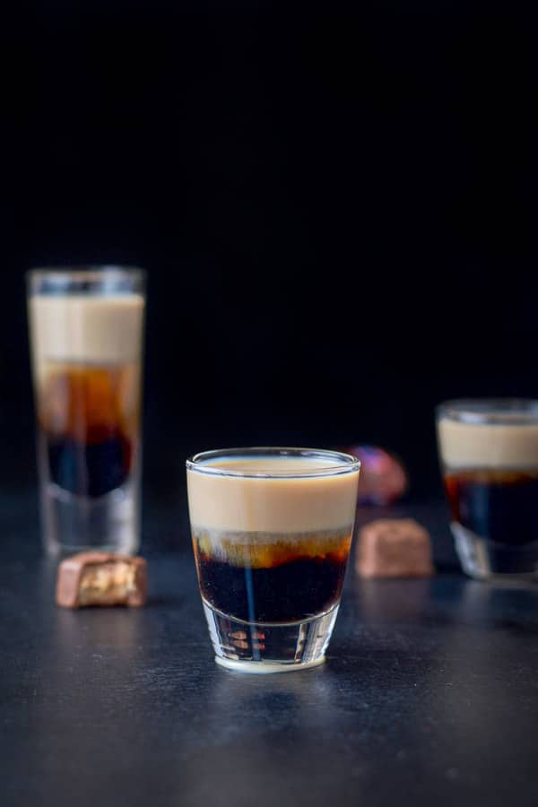 Three glasses filled with the shot with snickers in the background