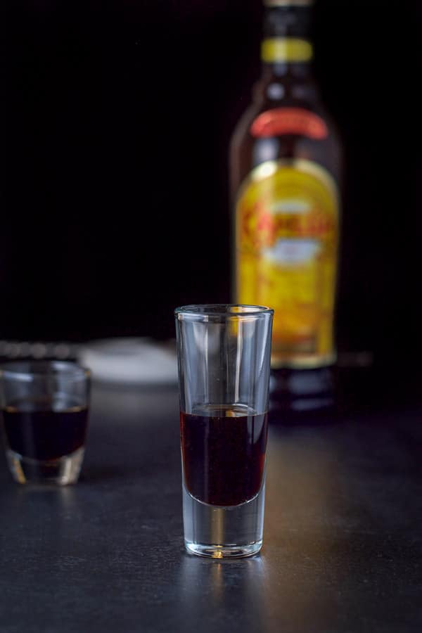 Kahlúa layered in the glasses with the bottle and spoon in the background