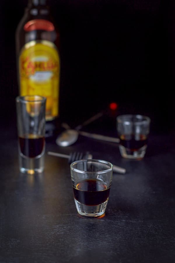 Kahlua poured with the bottle, pourer and spoons in the background