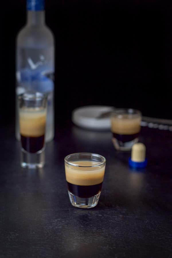 vodka layered in the three glasses with the bottle in the background