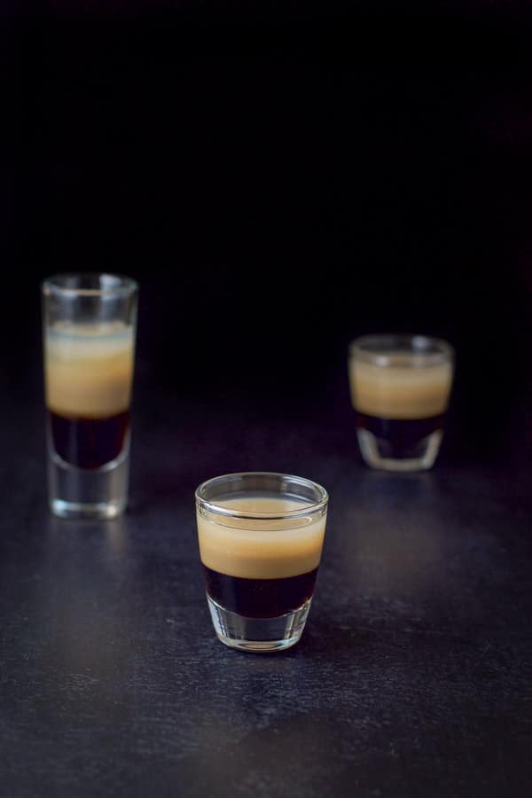 Short glass with the layered shot in front of the tall glass and another short glass
