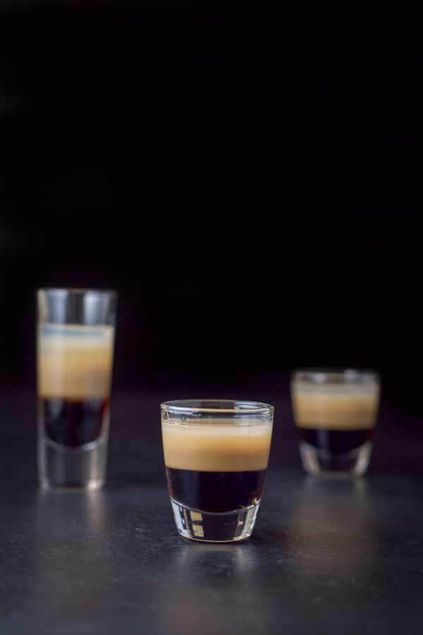 vertical view of the short glass filled with the peppermint shot. The other two glasses are behind it