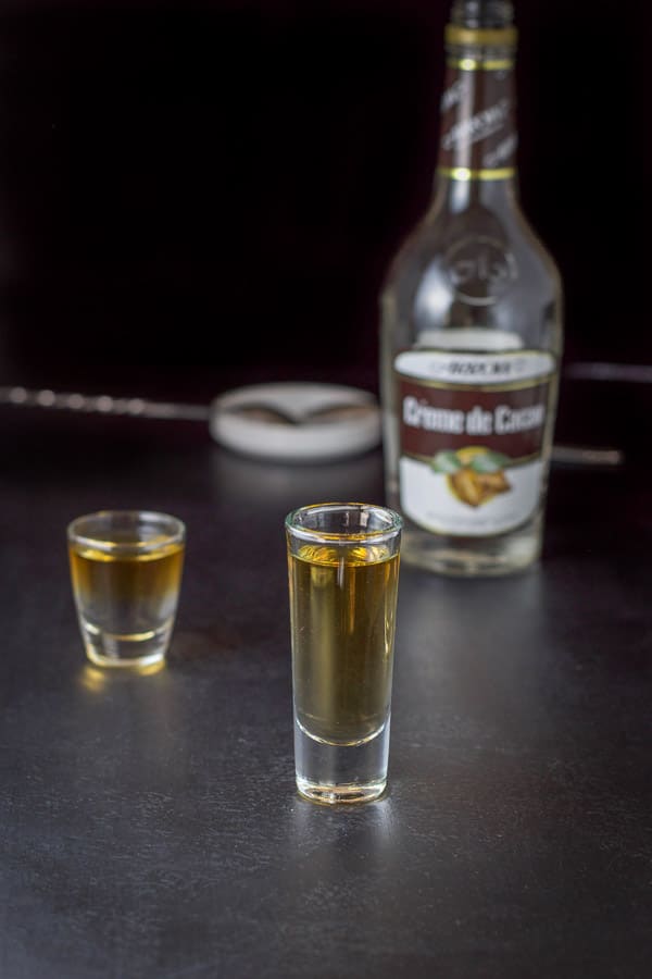 Creme de Cacao layered in the glasses with the bottle in the background