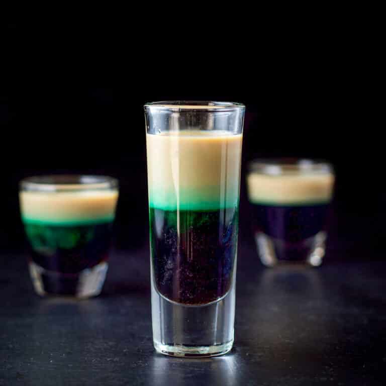 The tall glass filled with the layered shot - square