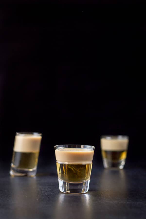 Vertical view of the faceted glass filled with layered shot with the other two glasses in the background