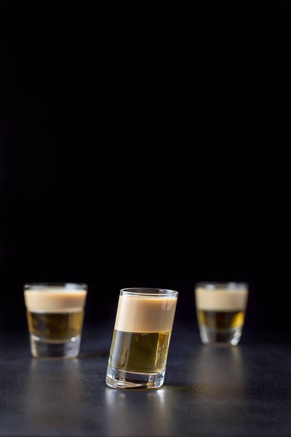 Slanted glass filled with the two layered shot. There are the other two glasses in the background