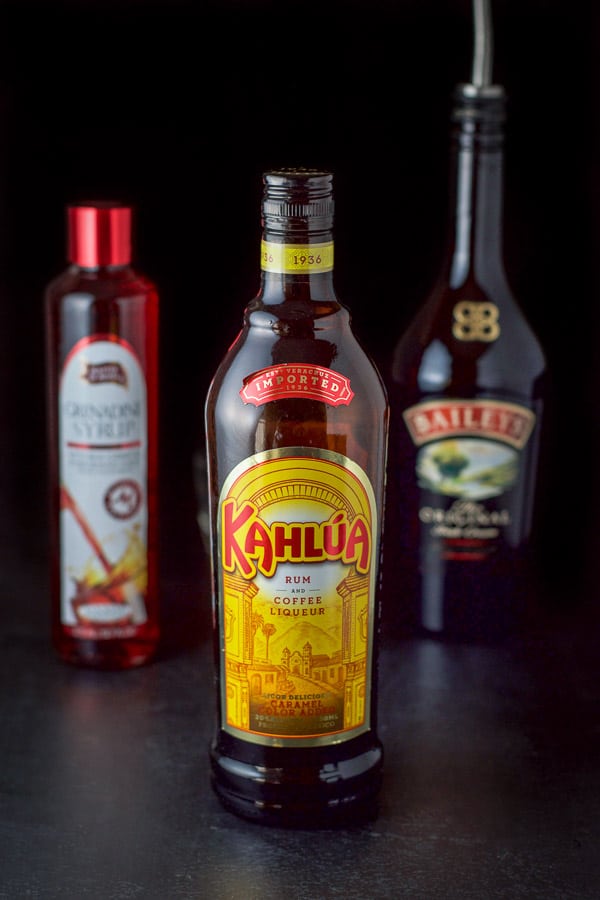 Kahlúa, Baileys and grenadine on a black table