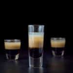 Vertical view of the tall glass filled with the peppermint shot with two other glasses behind it - square