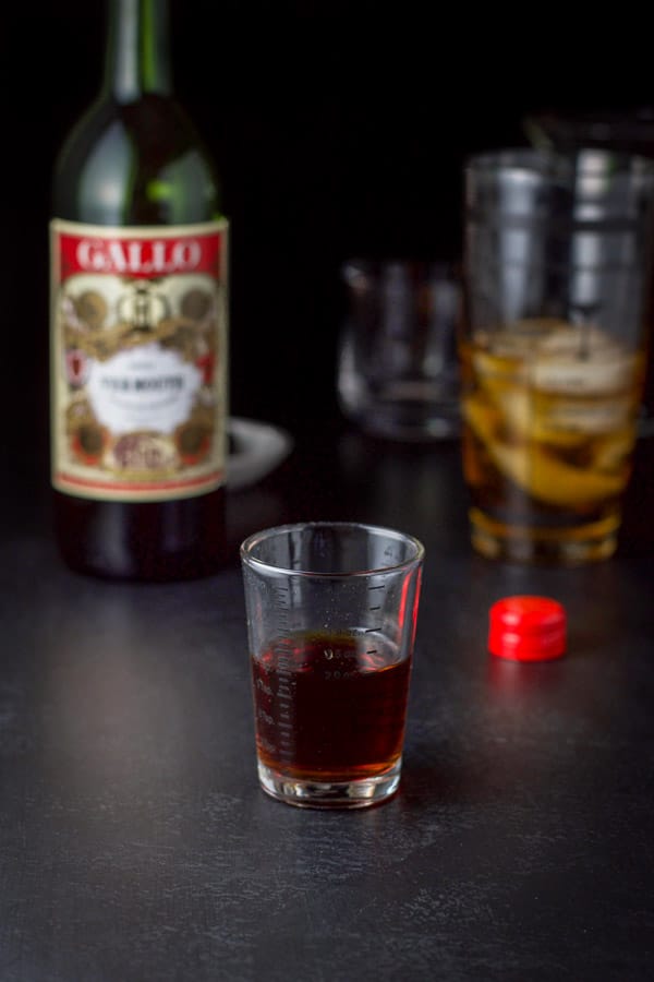 sweet vermouth measured out with the bottle, shaker and glass in the background