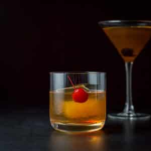Vertical view of the short glass with a red cherry and the cocktail - square