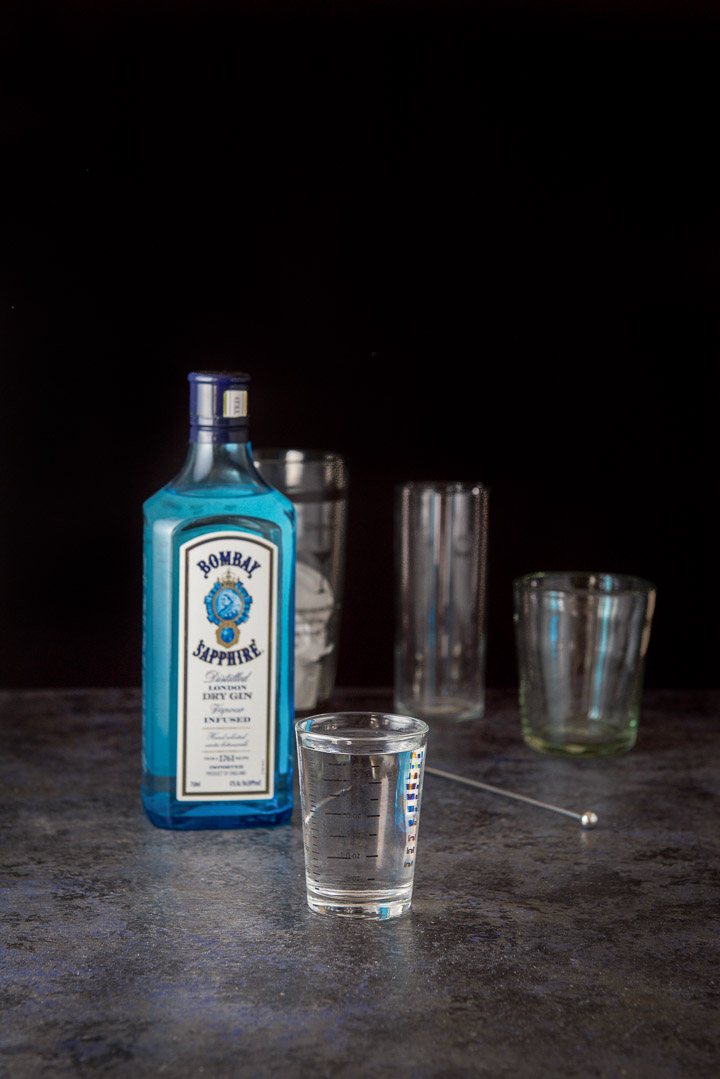 Gin measured out with the bottle, shaker and glasses in the background