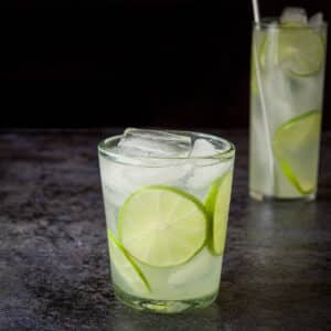 Short glass with the rickey in it with lime wheels as garnish - square