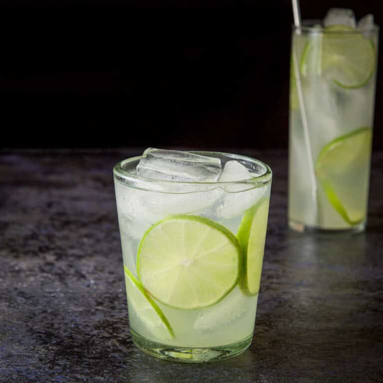 Short glass with the rickey in it with lime wheels as garnish - square