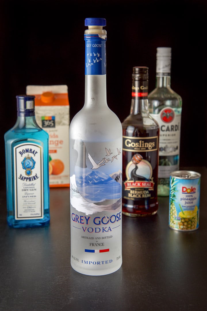 vodka, gin, dark rum, white rum, pineapple juice and orange juice on a black table