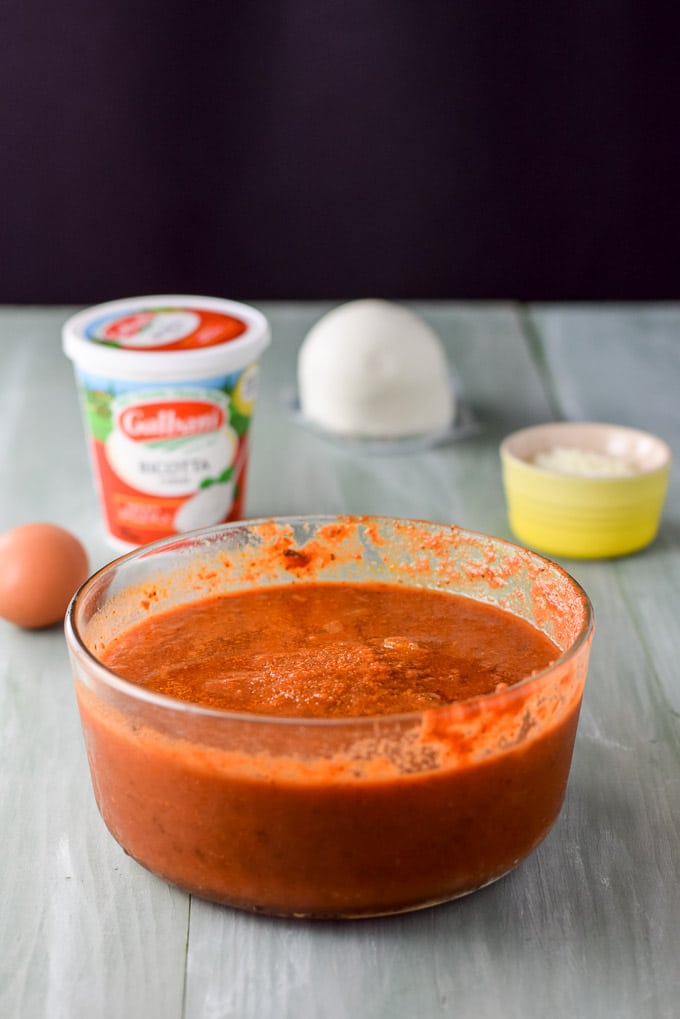 Red sauce, ricotta, egg, mozzarella and parmesan cheese on a green table