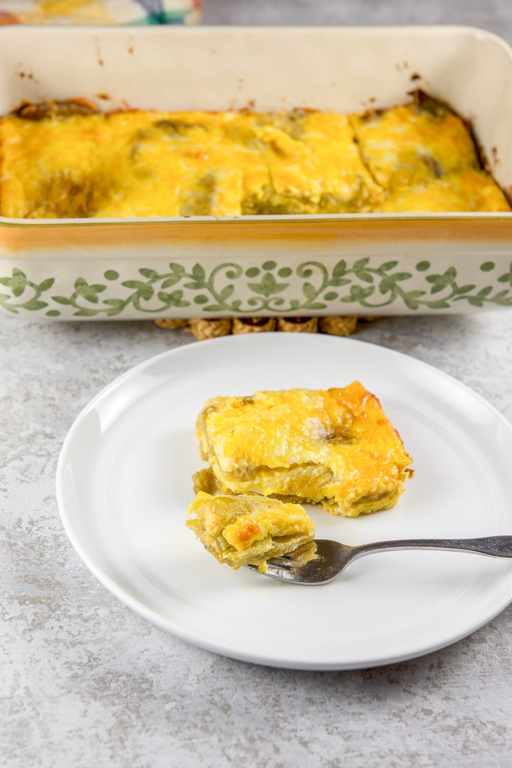 A forkful of chile relleno resting on a plate with the baking dish in the background
