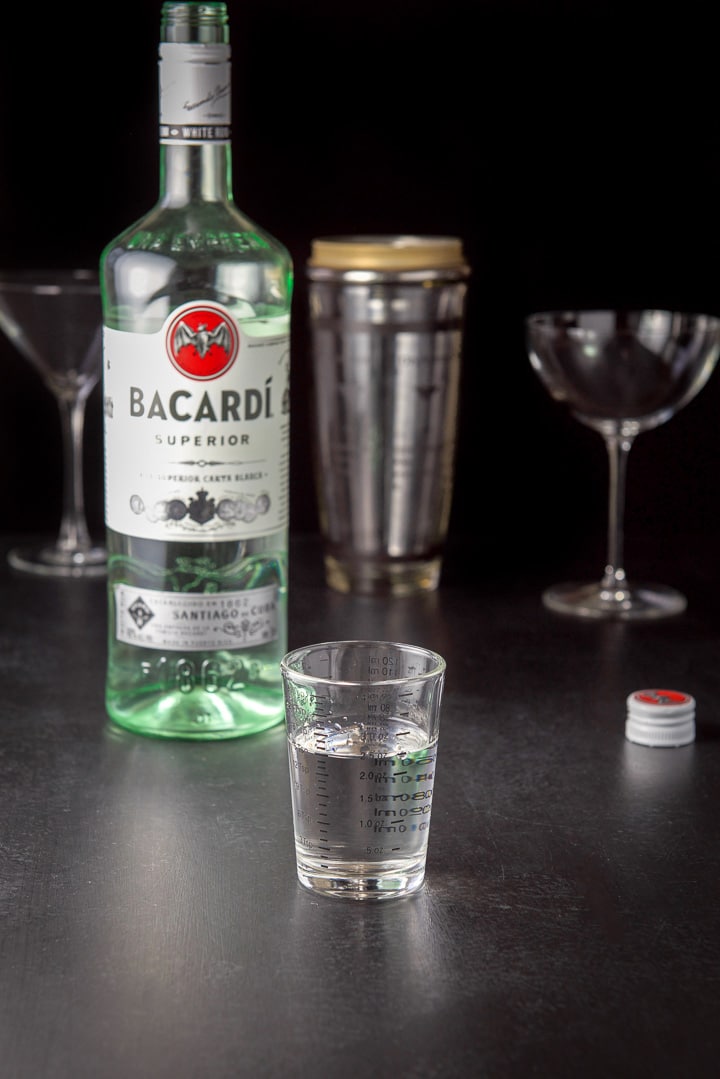 Rum poured out with the bottle, shaker and glasses on the table