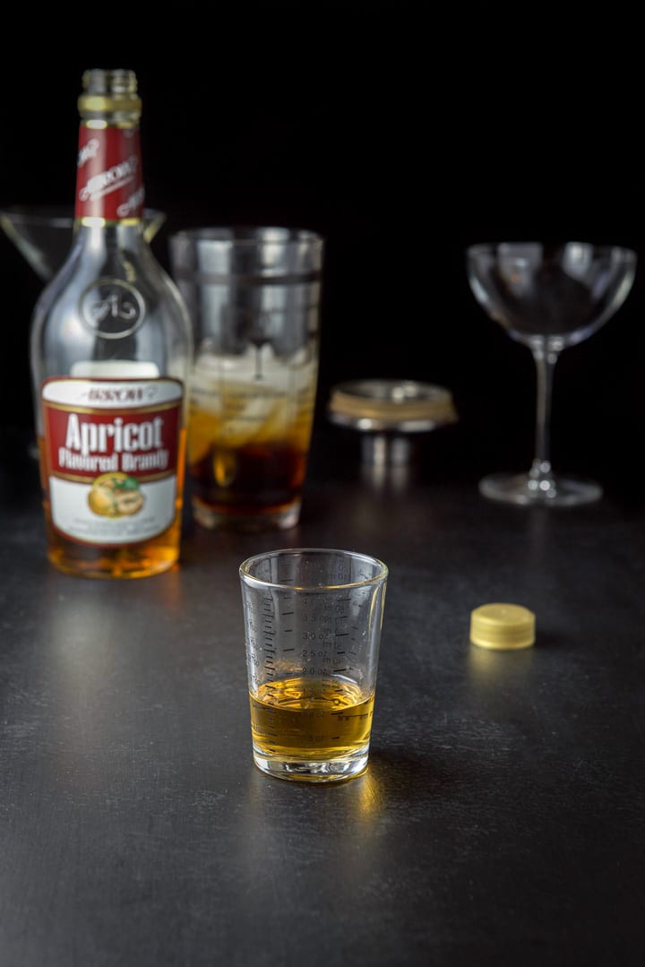 apricot brandy poured out with the bottle, half full shaker and glasses