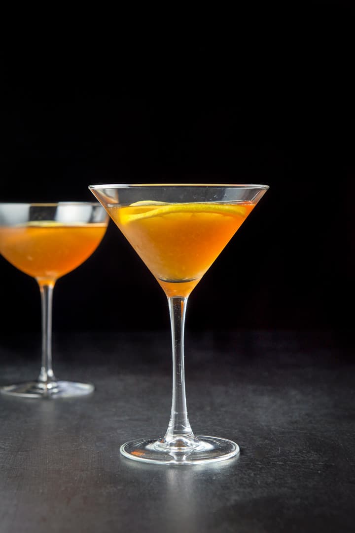 Vertical view of the classic glass in front. It's an amber liquid with lemon wheels as garnish