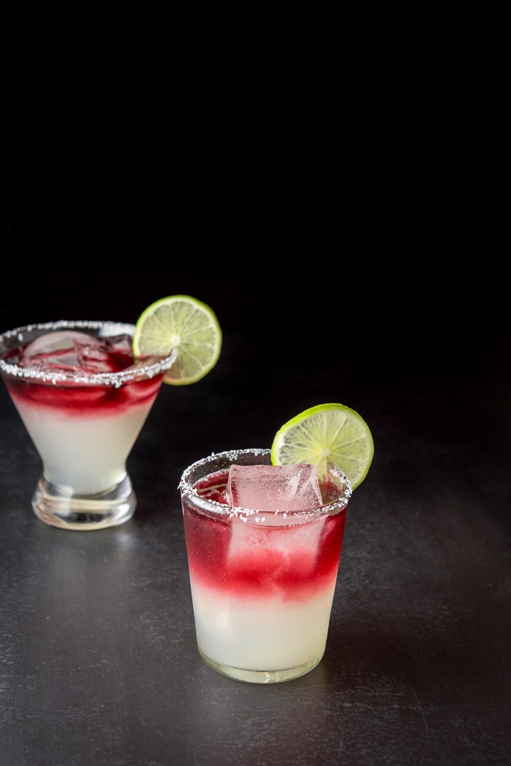 Two glasses with wine poured into the margarita. The lime wheels are on the rim