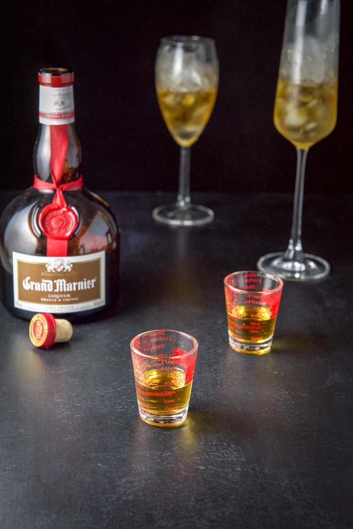 Grand Marnier measured with the bottle and glasses that are getting filled in the background