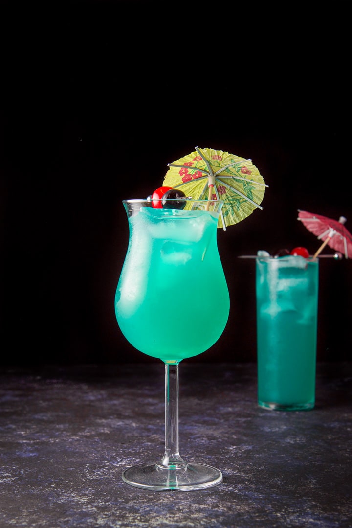 Vertical view of the tulip glass filled with the pretty blue drink with the garnish