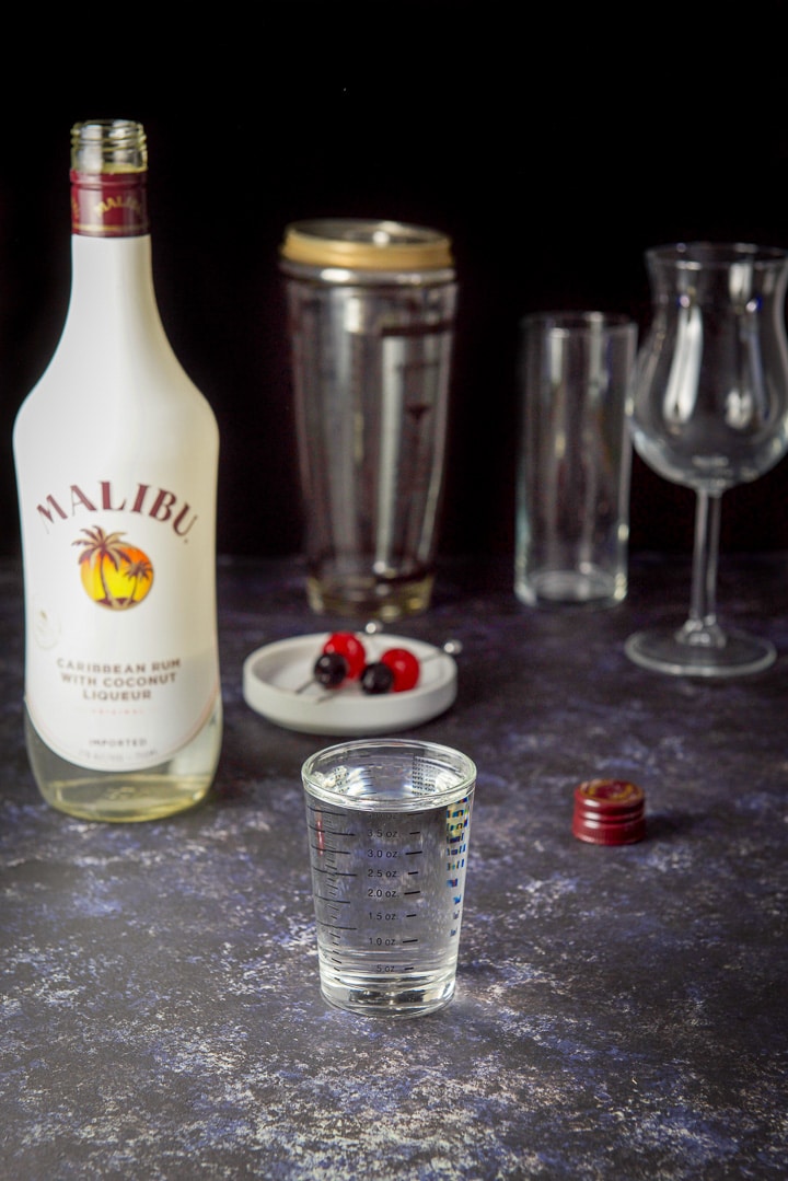 Coconut rum measured with the bottle, garnish, shaker and glasses