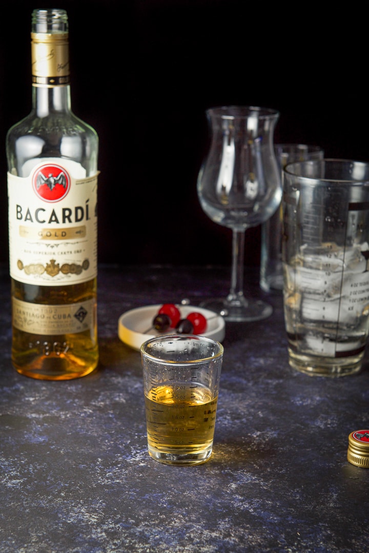 Gold rum measured with the shaker, bottle, and glasses