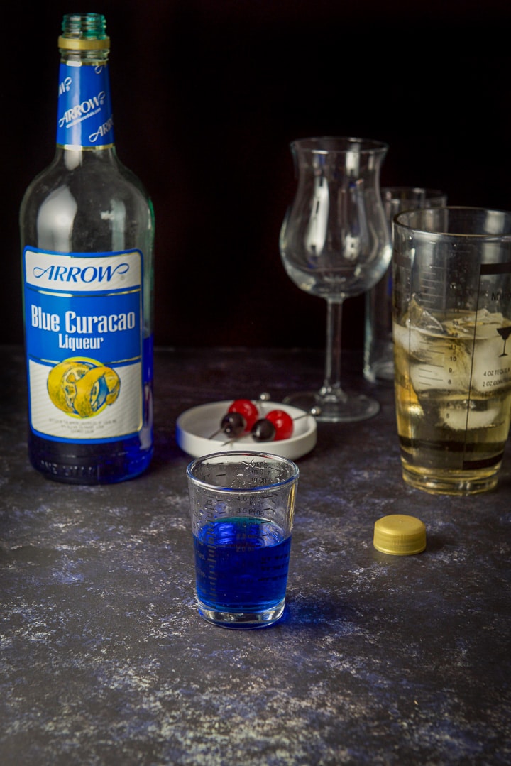 Blue curacao poured with the glasses, shaker and bottle