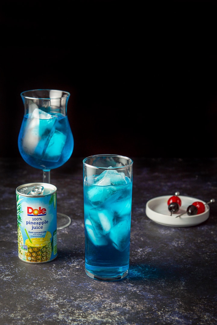The blue cocktail poured into the glasses waiting for the pineapple juice