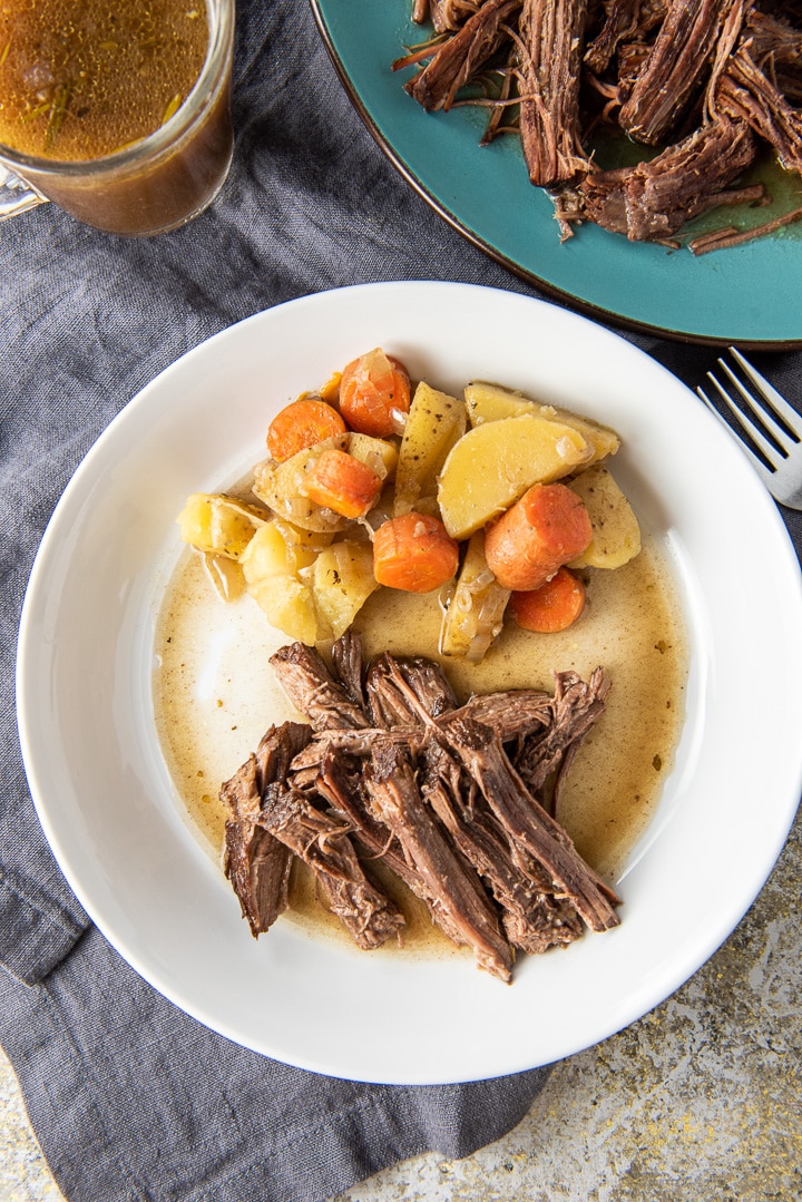 Overhead view of the shredded roast with veggies, gravy and more meat on a platter