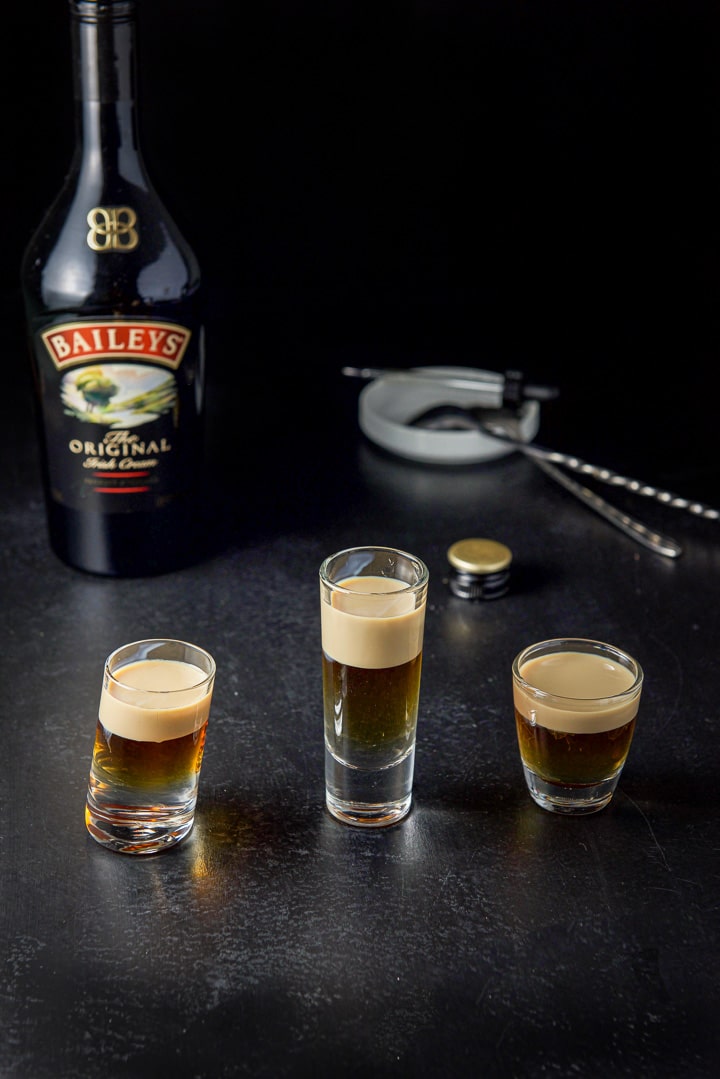 Baileys layered in the three glasses with the bottle in the background