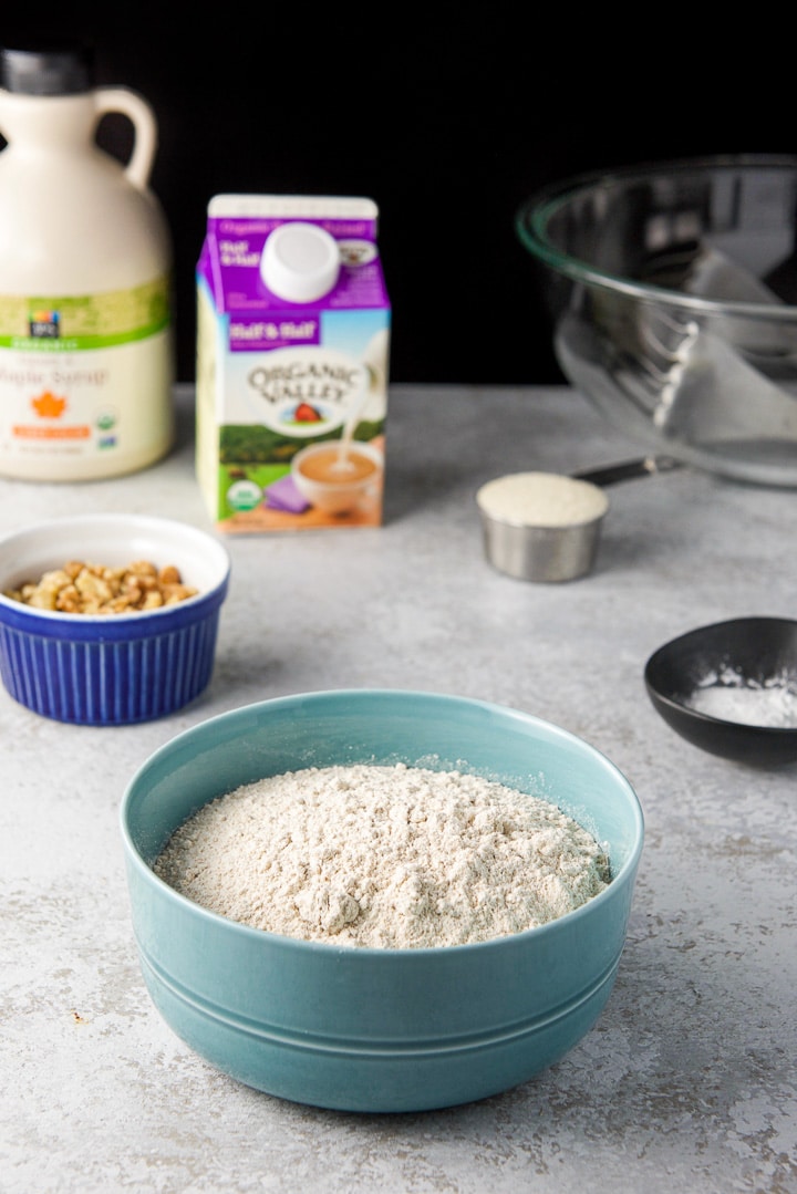 Spelt flour, walnuts, baking powder, sugar, cream and maple syrup with a bowl off to the side