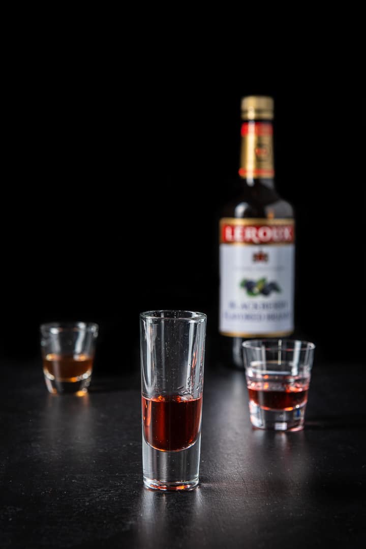 Blackberry brandy poured into the glass with the bottle in the background