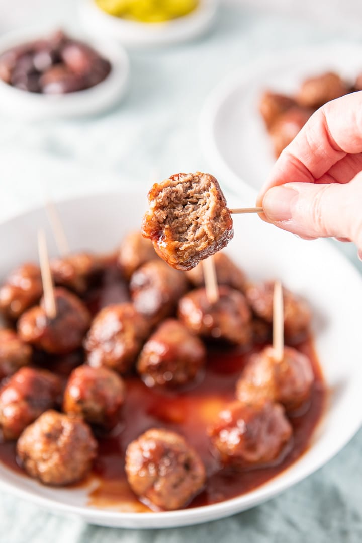 Bite taken out of one of the meatballs and held over the plate