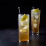 Collins glass with the amber cocktail in front of the wider taller glass - square
