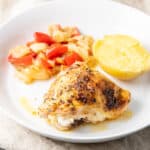 Square photo of the chicken thighs on a plate with vegetables and a potato
