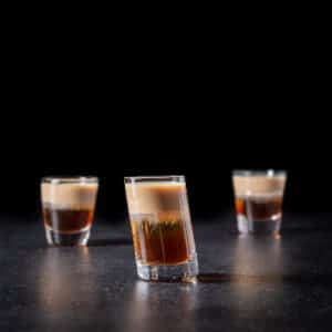Vertical view of the layered shot in the tilted glass with the two other glasses behind it - square