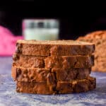 Four slices of date bread on top of each other with the loaf off to the right - square