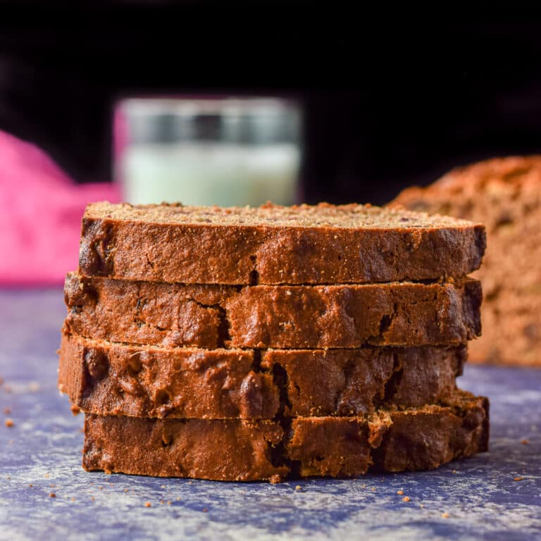 Four slices of date bread on top of each other with the loaf off to the right - square