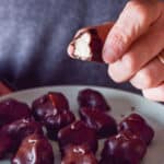 A male hand holding a mounds bar with a bite taken out of it - square