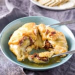A fork filled with puff pastry with cheese in a green bowl - square