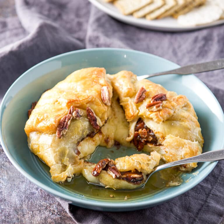 A fork filled with puff pastry with cheese in a green bowl - square