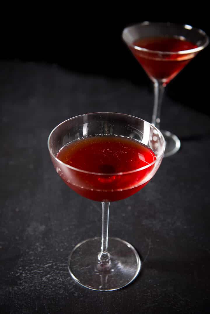 Two martini glasses, one bowl shaped and one classic shaped filled with the Manhattan