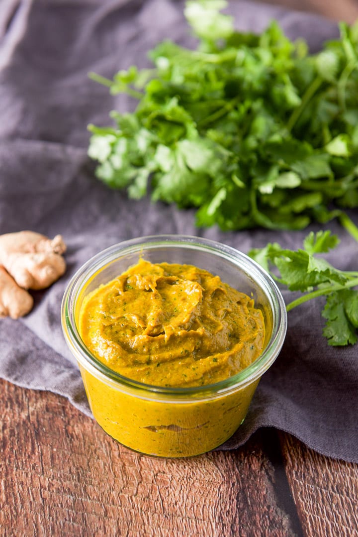Cilantro and ginger root on a grey napkin in back of some curry paste